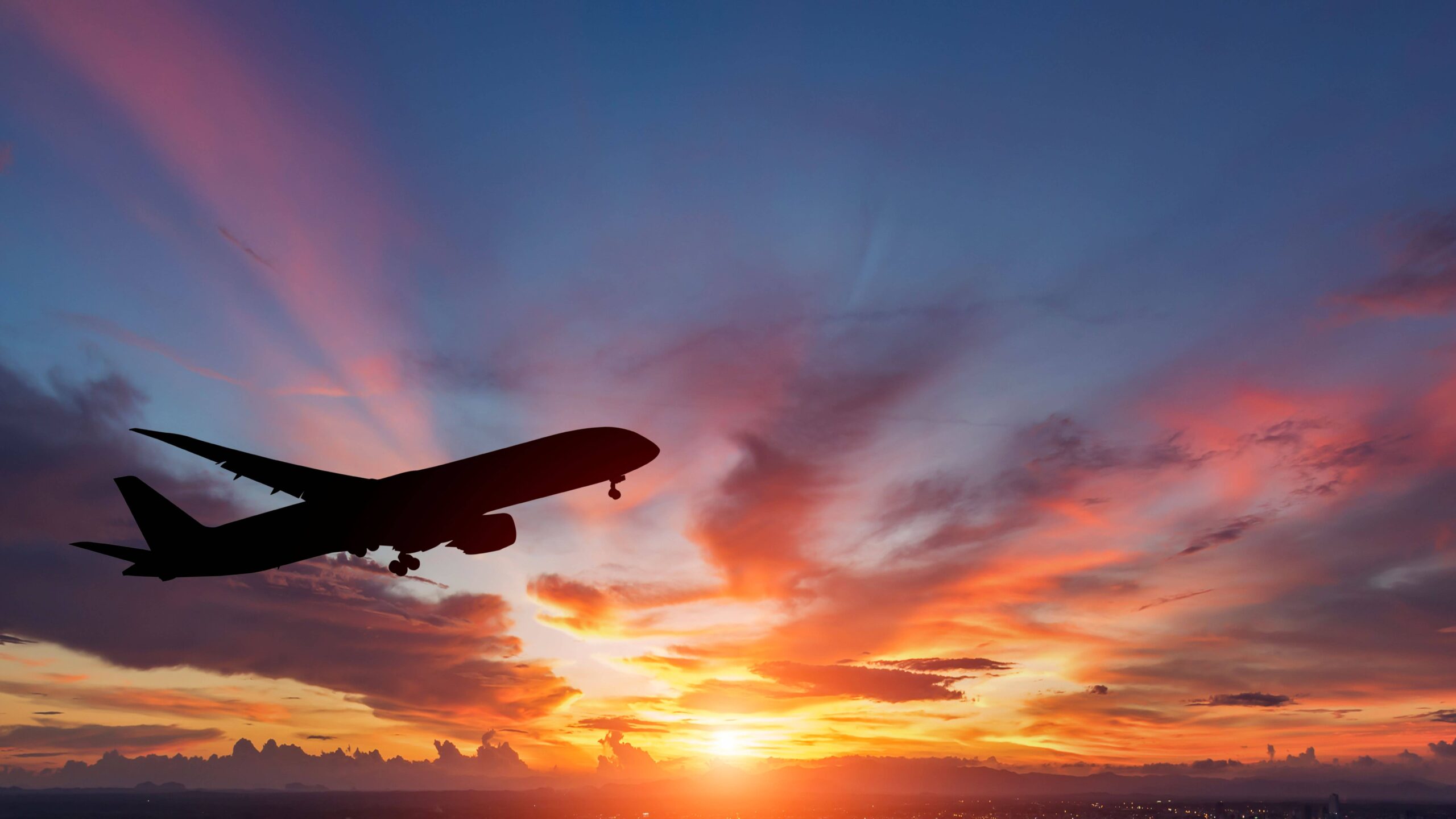 Silhouette of an airplane taking off against a sunset.